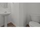 Powder room with pedestal sink, sleek faucet, elongated toilet, and wood-look floors at 5144 Rolling Meadow Blvd, Indianapolis, IN 46237
