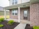 Inviting front porch with brick accents, supported columns, and well-manicured landscaping at 7824 Magnolia St, New Palestine, IN 46163