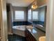 Bathroom with corner tub, double vanity, and dark green tile at 8531 Friendship Ln, Indianapolis, IN 46217