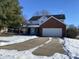 Two-story brick home with attached garage, partially covered porch, and snowy yard at 8531 Friendship Ln, Indianapolis, IN 46217