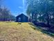 View of the backyard showing the grassy lot with mature trees and a glimpse of the home's exterior at 8660 S Peoga Rd, Trafalgar, IN 46181