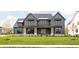 Gray farmhouse exterior with a stone base, light brown accents, and a manicured lawn at 14028 Grannan Ln, Carmel, IN 46074