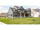 Gray farmhouse with a large front porch, stone accents, and a neatly landscaped yard at 14028 Grannan Ln, Carmel, IN 46074