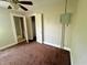 Bedroom with carpeting, a ceiling fan, and two open doors is in need of updating and repairs at 1610 Hoefgen St, Indianapolis, IN 46203