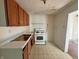 Old kitchen with wood cabinets, peeling paint, and a white gas range showing signs of wear and needed repairs at 1610 Hoefgen St, Indianapolis, IN 46203