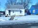 White bungalow with front porch, snow-covered yard, and blue neighboring house at 2508 E 4Th St, Anderson, IN 46012