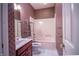 Pink bathroom with cherry vanity, shower and tub combo, and patterned walls at 4232 Bunting Ln, Columbus, IN 47203