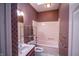Pink bathroom with cherry vanity, shower and tub combo, and patterned walls at 4232 Bunting Ln, Columbus, IN 47203