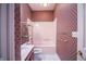 Pink bathroom with cherry vanity, shower and tub combo, and patterned walls at 4232 Bunting Ln, Columbus, IN 47203