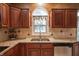 Close-up of a kitchen sink with granite countertops and wood cabinets under a window at 4232 Bunting Ln, Columbus, IN 47203