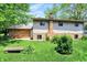 Backyard view showing the house's brick detail, chimney, and a lush green lawn with a concrete bench at 9157 Neptune Dr, Indianapolis, IN 46229