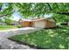 Home featuring a spacious driveway and lush green trees, offering shade and curb appeal at 9157 Neptune Dr, Indianapolis, IN 46229