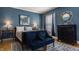 Blue bedroom featuring nightstands, a decorative mirror, two blue sitting chairs, and a well-lit comfortable space at 1319 N New Jersey St, Indianapolis, IN 46202