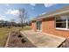 A concrete back patio area with a well-kept lawn and nice landscaping featuring a brick house with sliding glass door at 306 Vinewood N Dr, Brownsburg, IN 46112