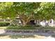 House nestled under a large tree, showcasing its brickwork and porch at 32 N Webster Ave, Indianapolis, IN 46219