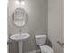 Modern powder room with a pedestal sink, round mirror and sleek fixtures at 5511 Sienna Ct, Brownsburg, IN 46112