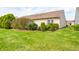 Spacious backyard with lush green grass and manicured trees with white window frames and beige siding at 7259 Registry Dr, Indianapolis, IN 46217