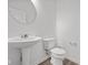 Cozy powder room with a stylish pedestal sink, a toilet, and a large, round mirror at 2310 Marjorie Way, Shelbyville, IN 46176