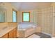Bright bathroom with natural wood vanity, soaking tub, glass block shower and tiled floor at 6012 Yellow Birch Ct, Avon, IN 46123