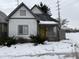Charming white house with gray accents, yellow door, and snowy yard at 243 E Caven St, Indianapolis, IN 46225