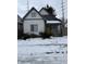 Charming white house with gray accents, yellow door, and snowy yard at 243 E Caven St, Indianapolis, IN 46225