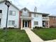 Inviting two-story condo featuring a landscaped yard, covered entry and light gray siding at 8104 Glenwillow Ln # 208, Indianapolis, IN 46278