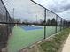 Fenced tennis court featuring blue and green surface with lighting at 8104 Glenwillow Ln # 208, Indianapolis, IN 46278