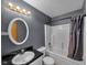 Bathroom featuring a shower-tub combo, dark vanity, oval mirror, and updated lighting at 11054 Dura Dr, Indianapolis, IN 46229