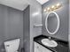 Cozy bathroom featuring a toilet, sink, black granite countertop, oval mirror and a gold colored light fixture at 11054 Dura Dr, Indianapolis, IN 46229
