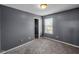 Cozy bedroom with neutral carpet and gray walls, with a window that provides natural light at 11054 Dura Dr, Indianapolis, IN 46229