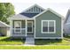 Charming green home with a inviting front porch and well-manicured landscaping at 1407 N Pershing Ave, Indianapolis, IN 46222