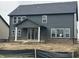 Two-story home with a dark gray exterior, covered patio, and unfinished yard at 19983 Boulder Brook Ln, Westfield, IN 46074