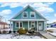 Charming teal house with a front porch, landscaping, and snow-covered lawn at 2015 Columbia Ave, Indianapolis, IN 46202
