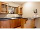 Wet bar featuring wooden cabinets, sink, countertop and bar seating that compliments the neutral wall color at 5508 Bay Landing Cir, Indianapolis, IN 46254