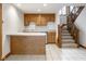 Basement kitchenette featuring wood cabinets, a breakfast bar, and staircase at 5508 Bay Landing Cir, Indianapolis, IN 46254
