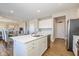 White kitchen with island, stainless steel appliances, and view to living room at 8576 Jeff Cir, Brownsburg, IN 46112