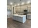 Open kitchen with large island, pendant lighting, stainless steel appliances, gray cabinets, and hardwood flooring at 525 Gilder Dr, Carmel, IN 46032