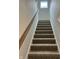 Carpeted stairs leading to the upper level, featuring a wooden handrail and white trim at 525 Gilder Dr, Carmel, IN 46032