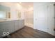 Modern bathroom with dual sinks, gray cabinets, wood-look floors, and a glass-enclosed shower at 6033 Granby Dr, Whitestown, IN 46075