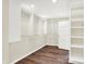 A walk-in closet with wooden floors, white walls, and custom shelving and clothing rods at 8602 Frontgate Ln, Indianapolis, IN 46256