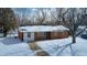 Charming single-story home features brick exterior, black door and snow covered front yard at 3647 Richelieu Rd, Indianapolis, IN 46226
