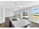 Kitchen with an island featuring a sink and marble countertops, leading to open living spaces at 385 N Post Oak Dr, Mooresville, IN 46158