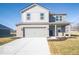Charming two-story home featuring a two-car garage, gray brick, gray siding, a covered porch and a well-manicured lawn at 5592 Cattail Branch Ln, Clayton, IN 46118