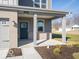 Close up of the home's entry featuring gray brick, gray siding, a covered porch and manicured landscaping at 5592 Cattail Branch Ln, Clayton, IN 46118