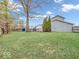 Large backyard with green lawn, mature trees, evergreen trees, wooden deck, and gray siding home at 11237 Baycreek Dr, Indianapolis, IN 46236