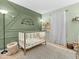 Charming Bedroom featuring a crib, stylish decor, and playful wall art on green accent wall at 11237 Baycreek Dr, Indianapolis, IN 46236