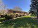 Well-maintained brick house featuring mature landscaping and an expansive green lawn at 6628 E Michigan St, Indianapolis, IN 46219