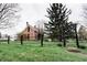 Classic red brick home with black trim and fencing, surrounded by a lush green lawn and mature trees at 301 Lowry St, Jamestown, IN 46147