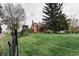 Scenic view of a classic red brick home and lush green lawn, framed by a black fence and mature trees at 301 Lowry St, Jamestown, IN 46147