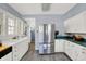 Spacious kitchen featuring stainless steel refrigerator, white cabinets, grey floor, and natural light at 5210 E Pleasant Run Parkway North Dr, Indianapolis, IN 46219